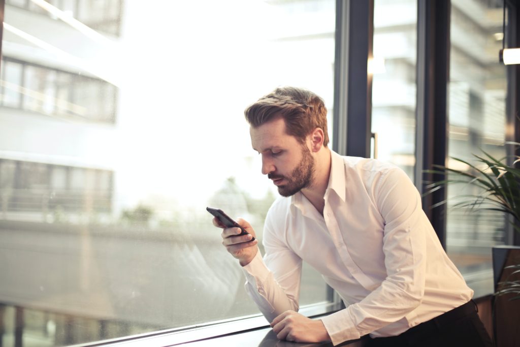 A small business owner checking his cell phone at the window to see if small business like his needs a lawyer